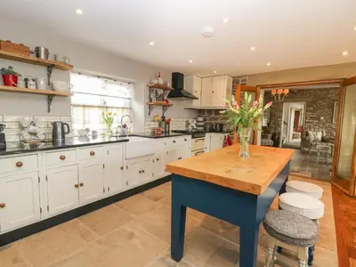 a large kitchen with white cabinets and a wooden table at Cuthbert Hill Farm in Preston