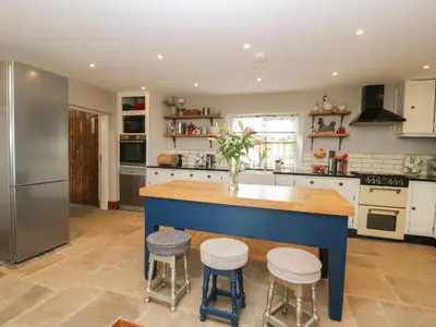 a kitchen with a blue island with stools at Cuthbert Hill Farm in Preston