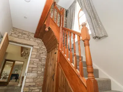 a wooden staircase in a home with a stone wall at Cuthbert Hill Farm in Preston