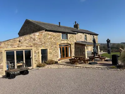 a stone building with picnic tables in front of it at Cuthbert Hill Farm in Preston