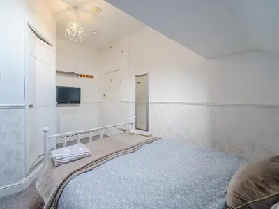 a white bedroom with a bed and a mirror at The Kings Landing Spa in Blackpool