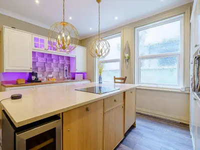 a large kitchen with purple walls and a large island at The Kings Landing Spa in Blackpool