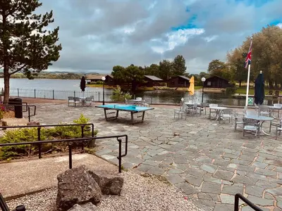 a patio with a ping pong table and chairs at Keer Side Lodge, Luxury lodge with private hot tub at Pine Lake Resort in Carnforth