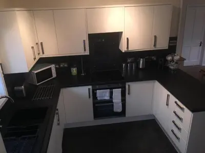a kitchen with black counter tops and white cabinets at Keer Side Lodge, Luxury lodge with private hot tub at Pine Lake Resort in Carnforth