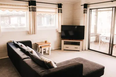 a living room with a couch and a flat screen tv at Keer Side Lodge, Luxury lodge with private hot tub at Pine Lake Resort in Carnforth