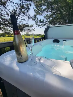 a bottle of champagne and a wine glass sitting on a table at Keer Side Lodge, Luxury lodge with private hot tub at Pine Lake Resort in Carnforth