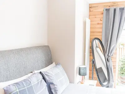 a bedroom with a bed and a mirror next to a window at The Lodge in Dalton in Furness