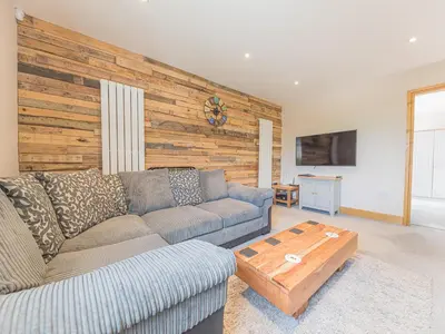 a living room with a couch and a wooden wall at The Lodge in Dalton in Furness