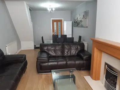 a living room with a leather couch and a fireplace at Hanwell House in Liverpool