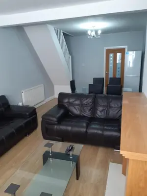 a living room with a black leather couch and a table at Hanwell House in Liverpool