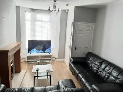 a living room with a leather couch and a flat screen tv at Hanwell House in Liverpool