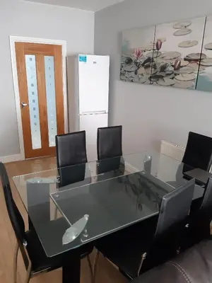 a glass table with four chairs and a refrigerator at Hanwell House in Liverpool