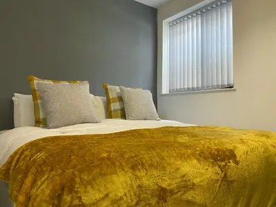 a bedroom with a large bed with a yellow blanket at Chelsea Suite Sasco Apartments in Blackpool