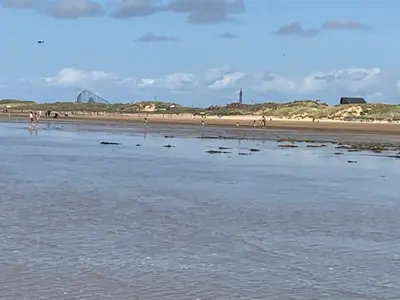 a beach with people walking on the sand and water at Beach Shore - SEA VIEWS in Lytham St Annes
