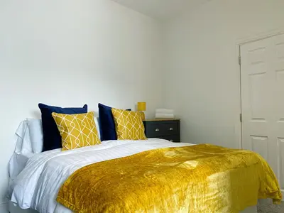 a bed with a gold blanket and pillows on it at Mayfair Suite - 3x Bathrooms Close to Seafront in Blackpool