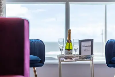 a bottle of champagne and two glasses on a table at Charles Alexander Short Stay - Highcliffe Apartments in Cleveleys