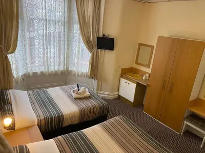 a hotel room with two beds and a television at Grange House Hotel in Blackpool