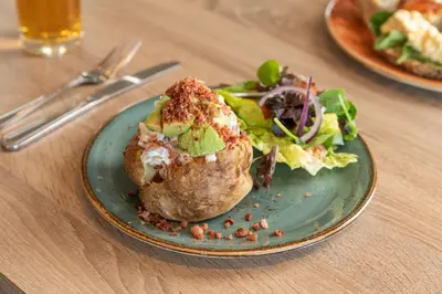 a green plate with a potato and salad on a table at Hampton By Hilton Blackburn in Blackburn
