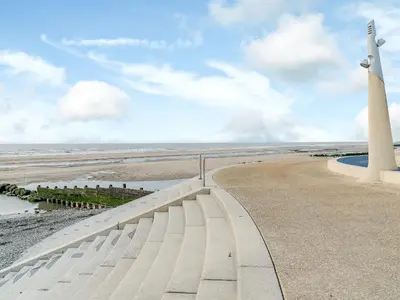 a lighthouse and a walkway next to the beach at Kays in Cleveleys