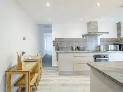 a kitchen with white cabinets and a wooden table at Kays in Cleveleys