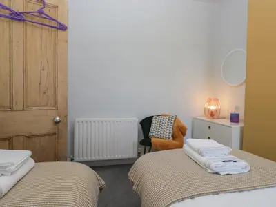 a bedroom with two twin beds and a chair at Number Thirty-Nine in Ulverston