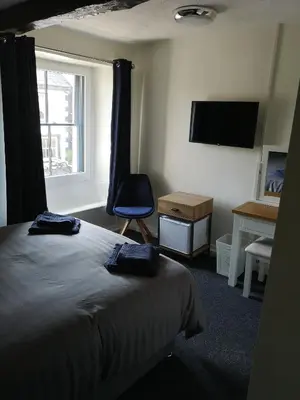 a bedroom with a bed and a chair and a window at Red Lion Rooms - Self Check In in Dalton in Furness