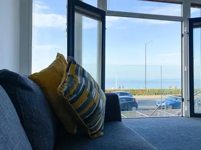 a blue couch with two pillows sitting in front of a window at Eden Escapes Serviced Apartments in Morecambe