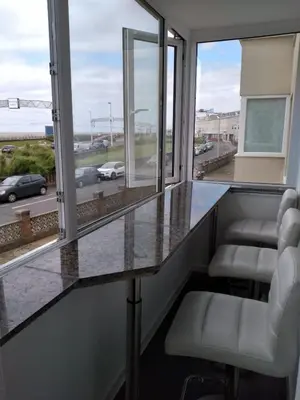 a room with a counter with chairs and windows at Sea-front Apartment home-from-home in Blackpool