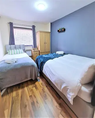 two beds in a bedroom with blue walls and wooden floors at Two-bedroom ground-floor apartment Self check-in in Liverpool