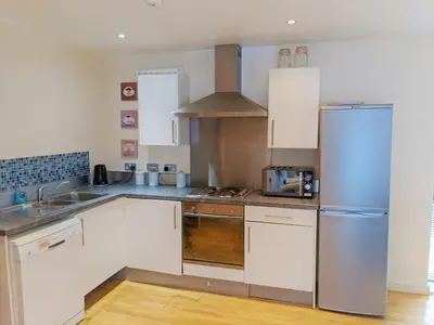 a kitchen with white cabinets and a stainless steel refrigerator at Two-bedroom ground-floor apartment Self check-in in Liverpool
