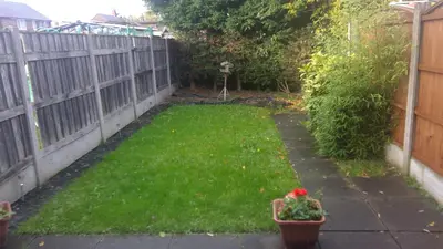 a backyard with a fence and a yard with green grass at Cosy house for business travel and pleasure in Bickershaw
