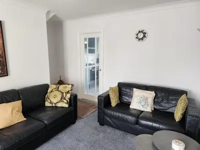 a living room with two black leather couches at Cosy house for business travel and pleasure in Bickershaw