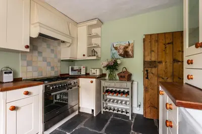 a kitchen with white cabinets and a stove top oven at Maggie Puddle Cottage in Cartmel