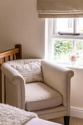 a chair sitting in a room with a window at Maggie Puddle Cottage in Cartmel