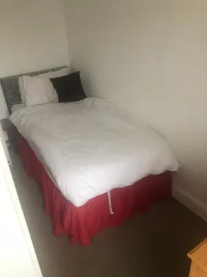 a bed with white sheets and a red skirt at Northern Pearl Hotel in Blackpool