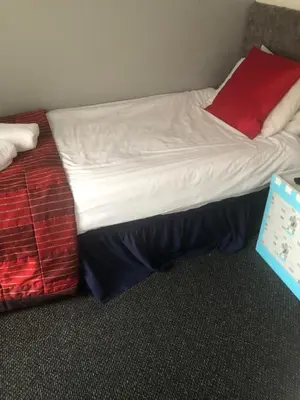 a bed with white sheets and a red pillow at Northern Pearl Hotel in Blackpool