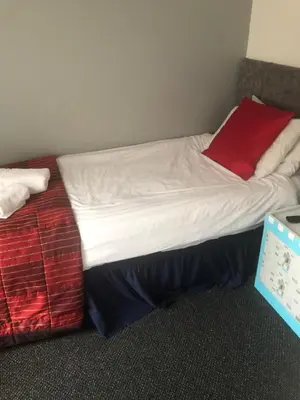 a bed with white sheets and a red pillow at Northern Pearl Hotel in Blackpool