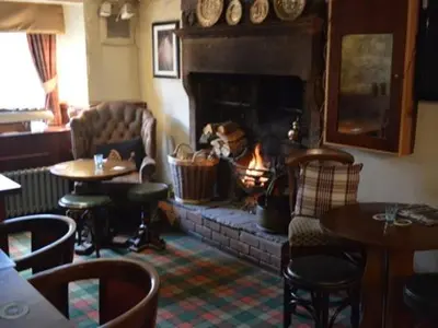 a living room with a fireplace and tables and chairs at The Engine Inn in Holker