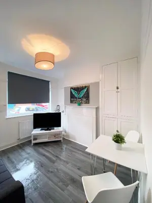 a living room with a television and a table and chairs at The Baltic Townhouses by Serviced Living Liverpool in Liverpool