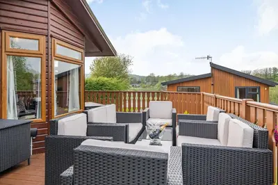 a patio with chairs and tables on a deck at Lakeview Lodge in Carnforth