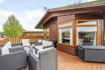 a deck with wicker chairs and a house at Lakeview Lodge in Carnforth