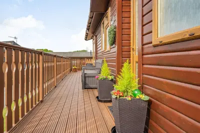 a wooden walkway with potted plants on the side of a building at Lakeview Lodge in Carnforth