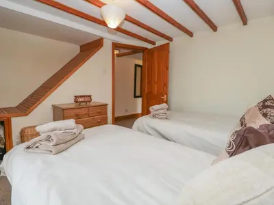a room with two beds and a dresser in it at Shipwreck Cottage in Millom