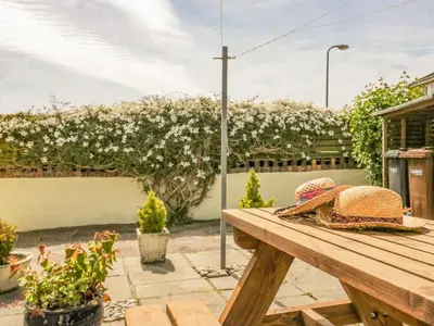a picnic table in a garden with flowers at Shipwreck Cottage in Millom