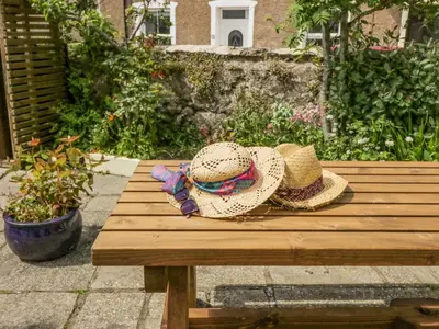 two hats are sitting on a wooden bench at Shipwreck Cottage in Millom