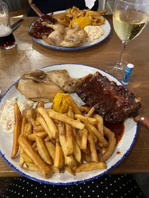 two plates of food with meat and french fries on a table at Nicks & Carmels by the sea in Heysham