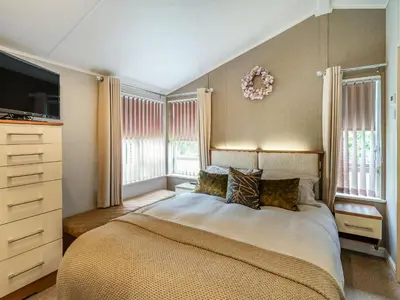 a bedroom with a bed and a tv and windows at Links Lodge in Grange Over Sands