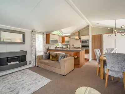 a kitchen and living room with a couch and a table at Links Lodge in Grange Over Sands