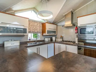 a large kitchen with white cabinets and a window at Links Lodge in Grange Over Sands