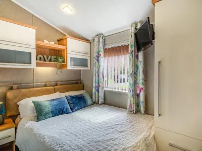 a small bedroom with a bed and a window at Links Lodge in Grange Over Sands